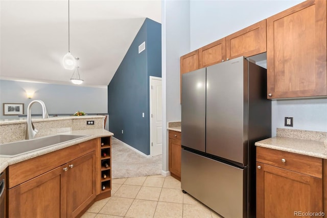 kitchen featuring a sink, brown cabinets, light countertops, and freestanding refrigerator