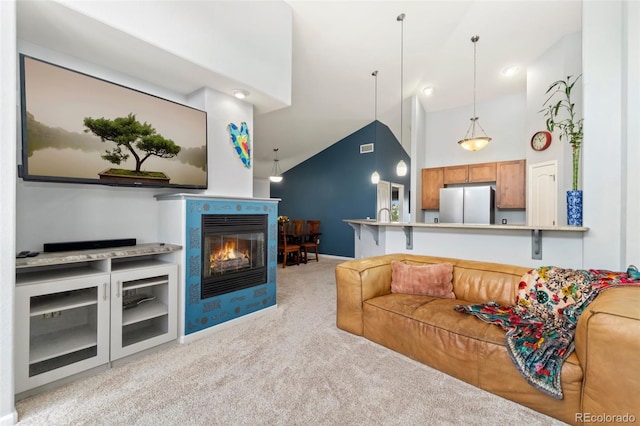 living room featuring visible vents, high vaulted ceiling, a glass covered fireplace, carpet flooring, and baseboards