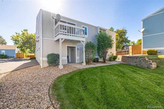 back of house with a balcony, central air condition unit, and a yard