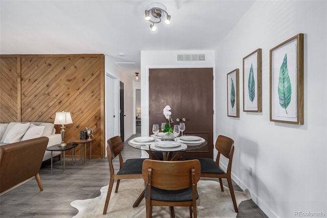 dining area featuring hardwood / wood-style flooring and wooden walls