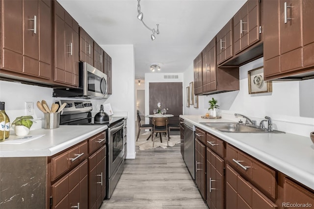 kitchen featuring appliances with stainless steel finishes, dark brown cabinetry, light hardwood / wood-style floors, and sink