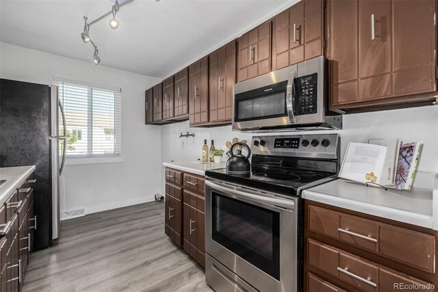 kitchen with light hardwood / wood-style flooring, dark brown cabinets, and appliances with stainless steel finishes