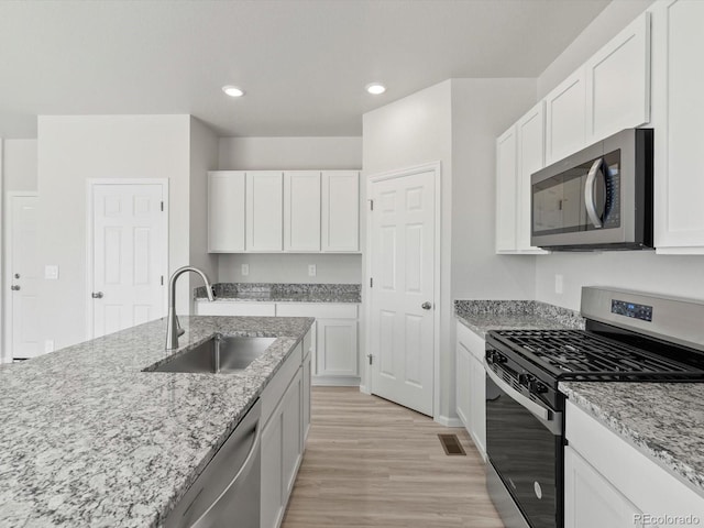 1134 Thunder Pass Rd, Severance, CO 80550 - kitchen with stainless steel appliances, light wood-style floors, white cabinetry, and recessed lighting