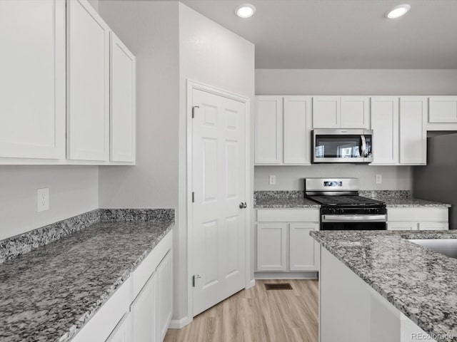 1134 Thunder Pass Rd, Severance, CO 80550 - kitchen featuring stainless steel appliances, white cabinets, light stone counters, light wood finished floors, and recessed lighting