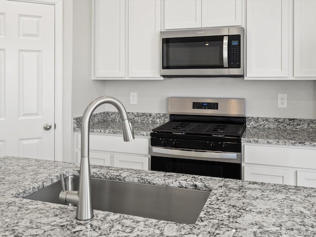 1134 Thunder Pass Rd, Severance, CO 80550 - kitchen featuring appliances with stainless steel finishes, white cabinetry, and light stone counters