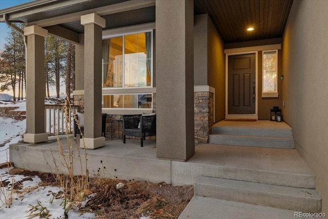 snow covered property entrance with a porch