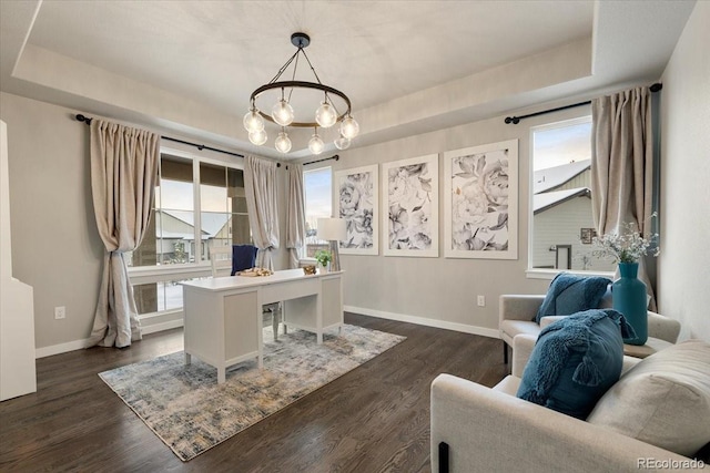 office featuring a raised ceiling, a wealth of natural light, dark hardwood / wood-style floors, and an inviting chandelier