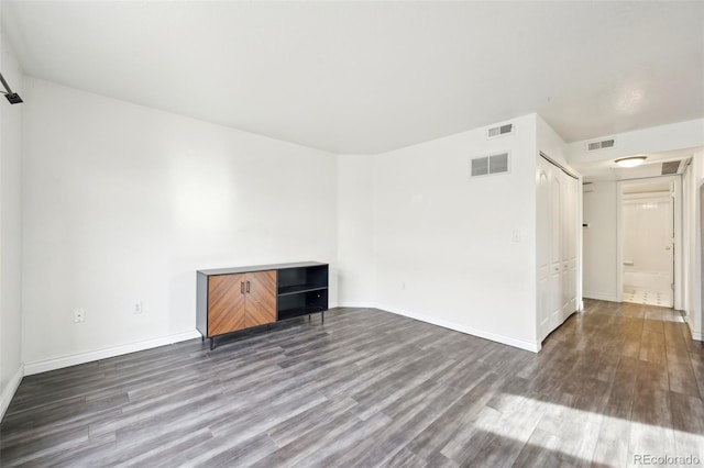 unfurnished living room featuring visible vents and wood finished floors