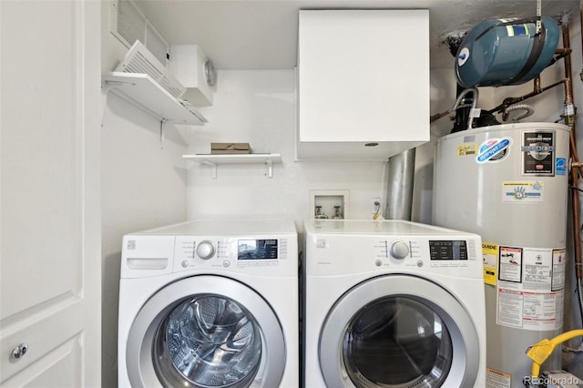 clothes washing area with washing machine and dryer, water heater, and laundry area