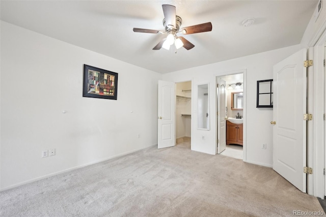 unfurnished bedroom with a sink, a spacious closet, a closet, light colored carpet, and connected bathroom