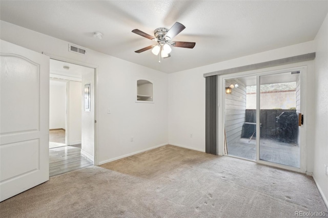 carpeted spare room with a ceiling fan, visible vents, and baseboards