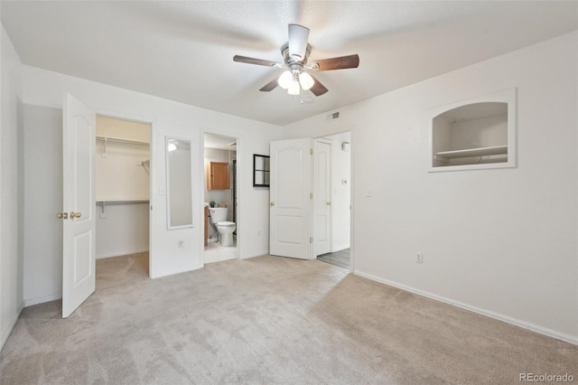 unfurnished bedroom featuring visible vents, carpet floors, a spacious closet, a closet, and connected bathroom