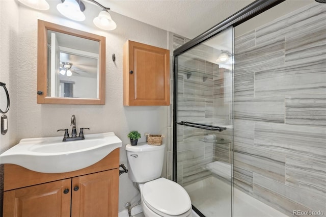 full bath featuring vanity, toilet, a textured wall, and a stall shower