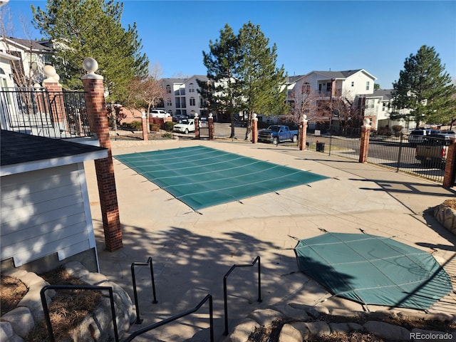 view of swimming pool with a fenced in pool, a residential view, fence, and a patio area