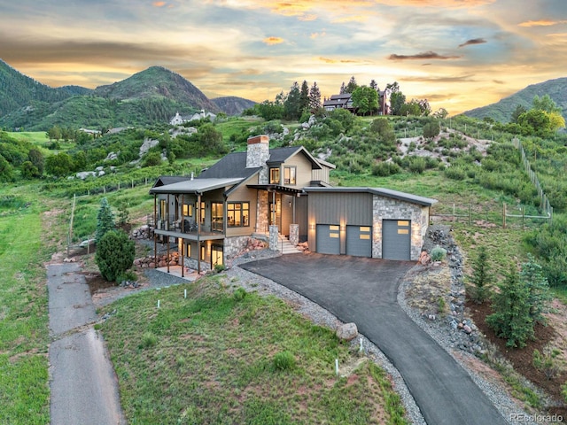 12947 Lazy Dog Ln, Littleton, CO 80127 - contemporary home featuring stone siding, a mountain view, a chimney, and asphalt driveway