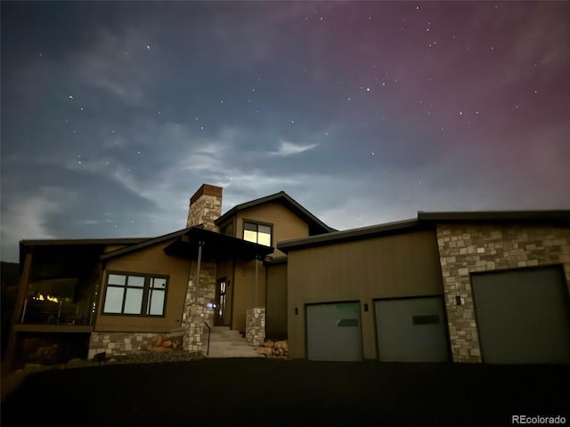 12947 Lazy Dog Ln, Littleton, CO 80127 - view of front facade with stone siding, an attached garage, a chimney, and asphalt driveway