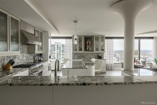 1133 14th St Unit 3430, Denver, CO 80202 - kitchen with wall chimney range hood, stainless steel stove, light stone countertops, and backsplash