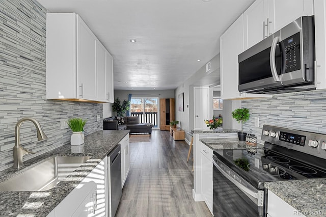 kitchen with sink, stainless steel appliances, backsplash, dark stone countertops, and white cabinets