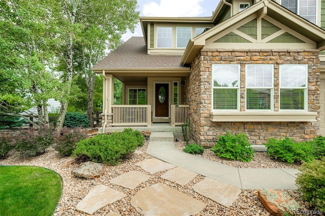 property entrance with a porch, stone siding, and a shingled roof