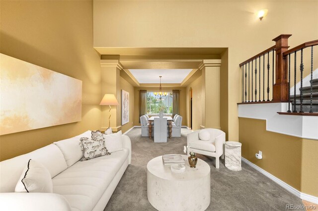 carpeted living area featuring a chandelier, baseboards, and stairs