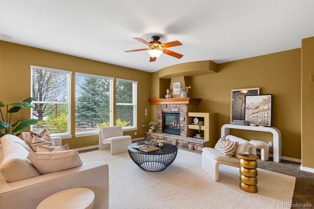 living room featuring baseboards, carpet floors, a fireplace, and ceiling fan