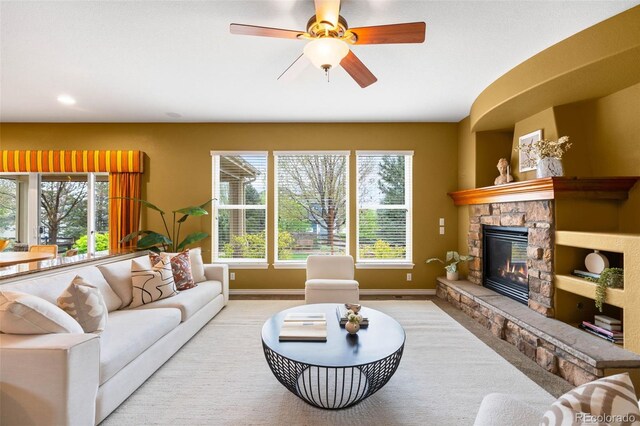 living area with baseboards, a stone fireplace, ceiling fan, and recessed lighting