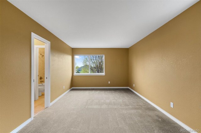 carpeted spare room featuring baseboards