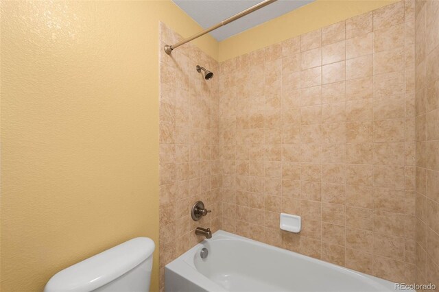 full bathroom featuring toilet, tub / shower combination, and a textured wall