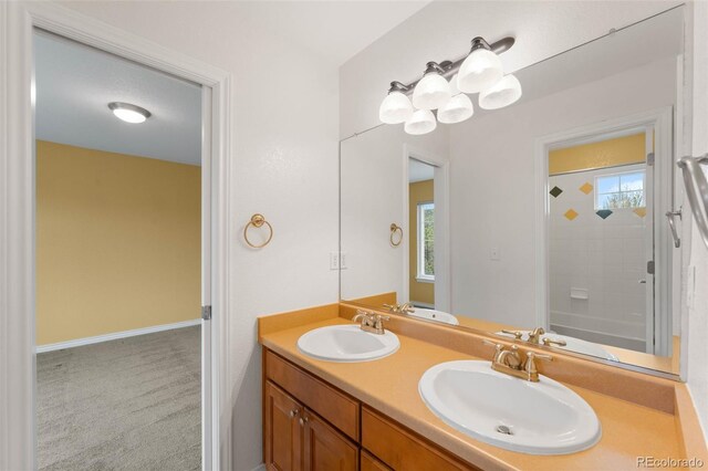 full bath with double vanity, a shower, healthy amount of natural light, and baseboards