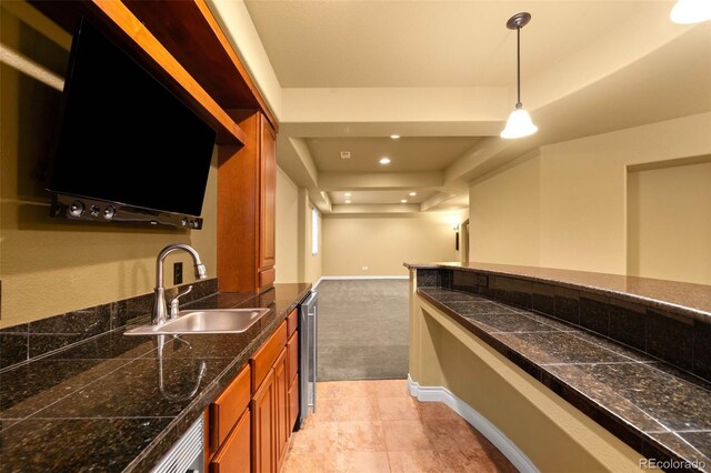 bar area featuring a sink, a raised ceiling, pendant lighting, baseboards, and light colored carpet