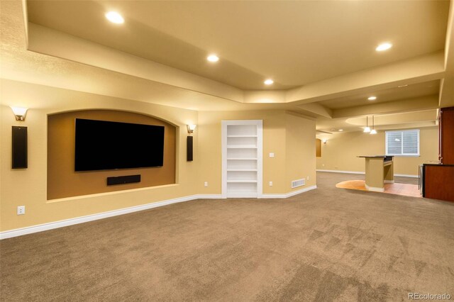 unfurnished living room featuring carpet, baseboards, recessed lighting, built in shelves, and a tray ceiling