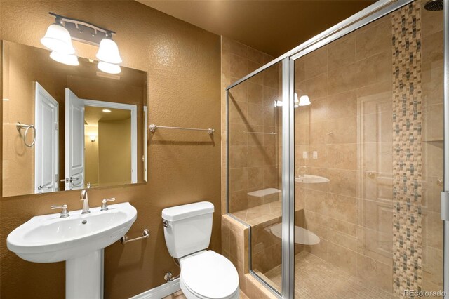 bathroom with a shower stall, toilet, a textured wall, and a sink