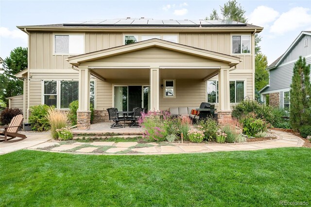 back of house with a patio, a yard, solar panels, and stone siding