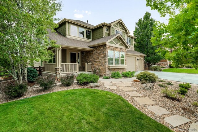 view of front of property featuring concrete driveway, stone siding, covered porch, a front lawn, and roof with shingles
