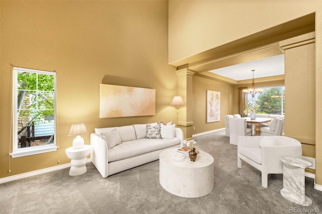 living area with a chandelier, baseboards, carpet floors, and a high ceiling