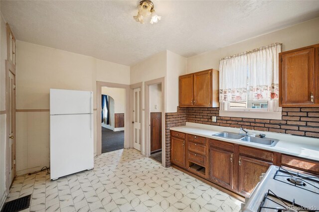 117 S Limit St, Colorado Springs, CO 80905 - kitchen with freestanding refrigerator, a sink, light flooring, gas range oven, and brown cabinetry