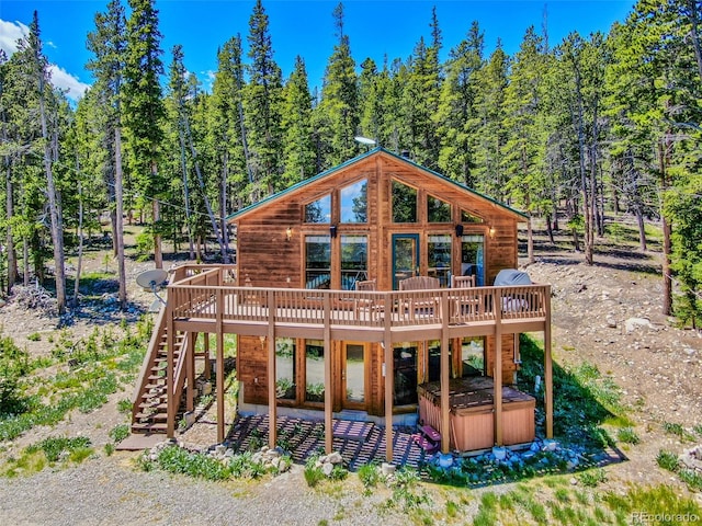 back of property featuring a deck and a hot tub