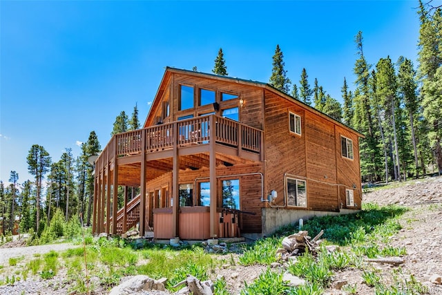 rear view of property featuring a hot tub and a wooden deck