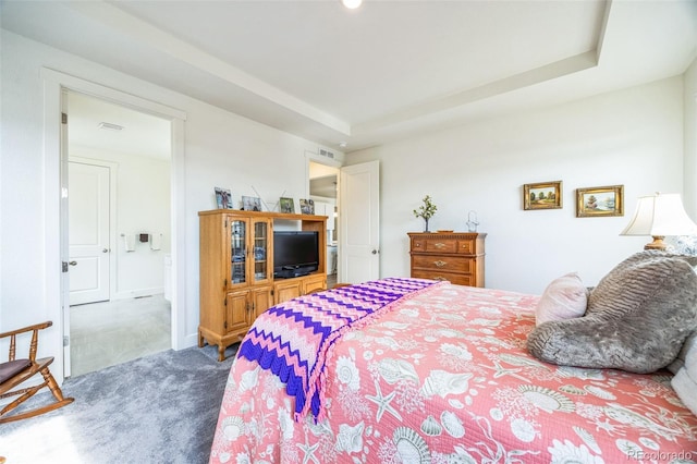 bedroom with carpet floors and a raised ceiling