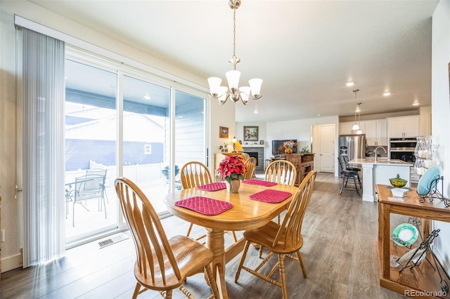 dining room featuring an inviting chandelier, sink, and light wood-type flooring