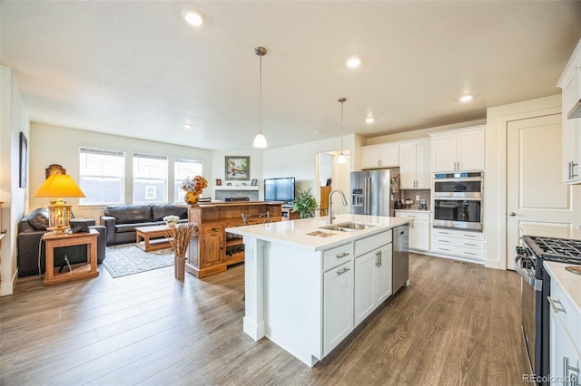 kitchen featuring stainless steel appliances, white cabinetry, and an island with sink