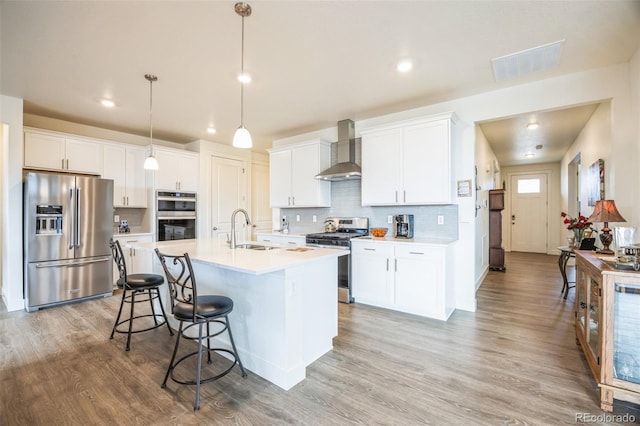 kitchen with sink, white cabinets, wall chimney exhaust hood, and appliances with stainless steel finishes