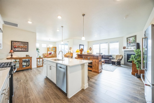 kitchen featuring sink, a center island with sink, appliances with stainless steel finishes, pendant lighting, and white cabinets