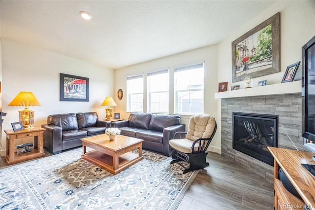 living room with a tiled fireplace and wood-type flooring