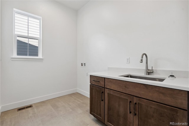 interior space with cabinet space, baseboards, visible vents, washer hookup, and a sink