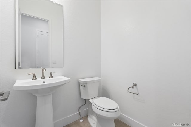 bathroom with toilet, baseboards, and a sink