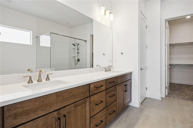 bathroom featuring double vanity, a stall shower, a sink, and a walk in closet