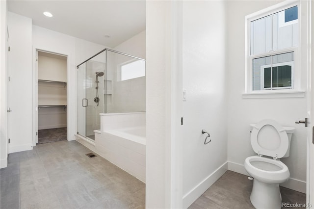 bathroom featuring a garden tub, a spacious closet, toilet, a stall shower, and baseboards