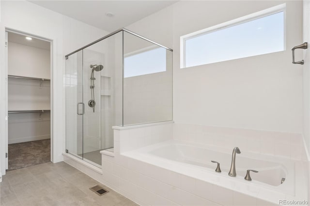 bathroom with a shower stall, visible vents, a walk in closet, and a bath