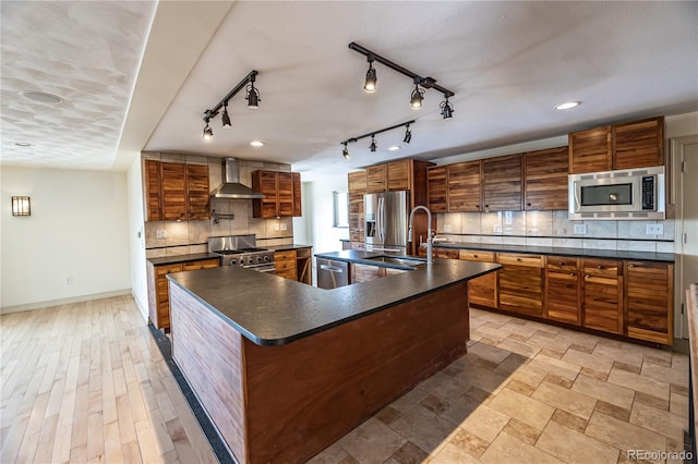 kitchen with a large island, a textured ceiling, backsplash, stainless steel appliances, and wall chimney range hood